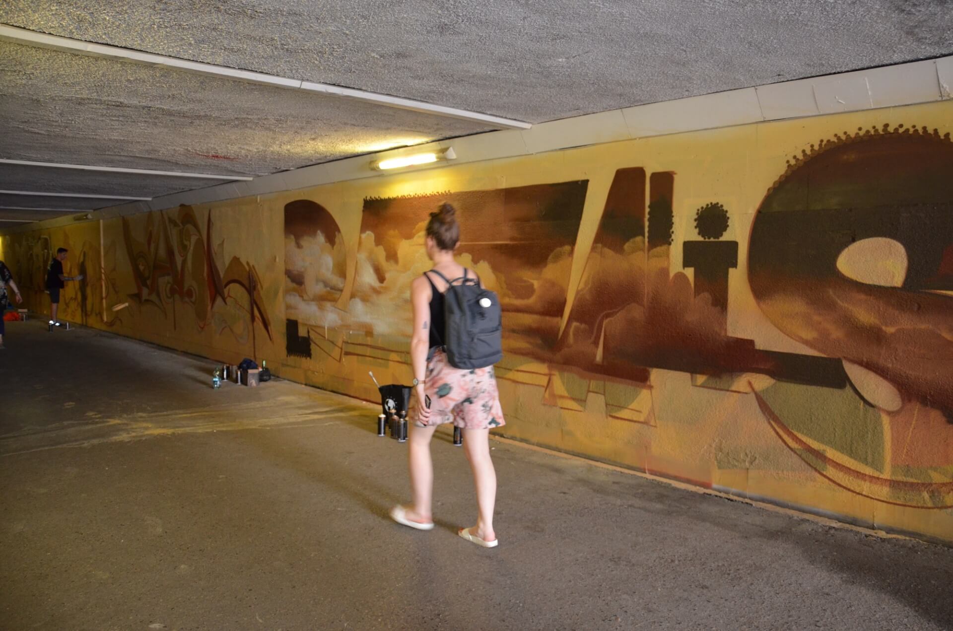 Artyści malują mural w przejściu pod torami łączącym ulice Wojewódzką i 1