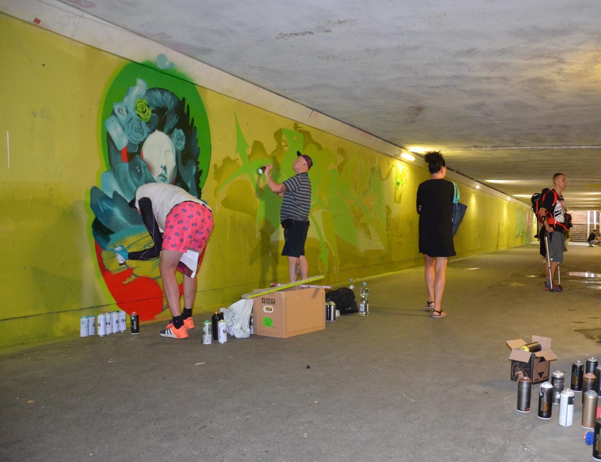 Artyści malują mural w przejściu pod torami łączącym ulice Wojewódzką i