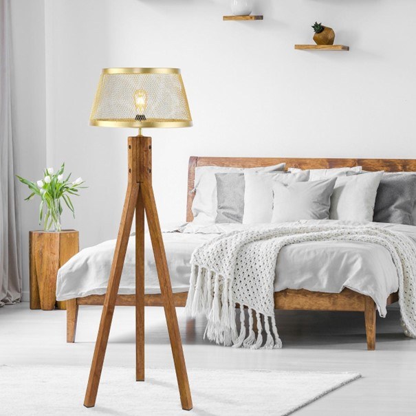 Lampa z mosiężnym abażurem na drewnianym trójnogu to interesujący pomysł na rozświetlenie, upiększenie i ocieplenie sypialni